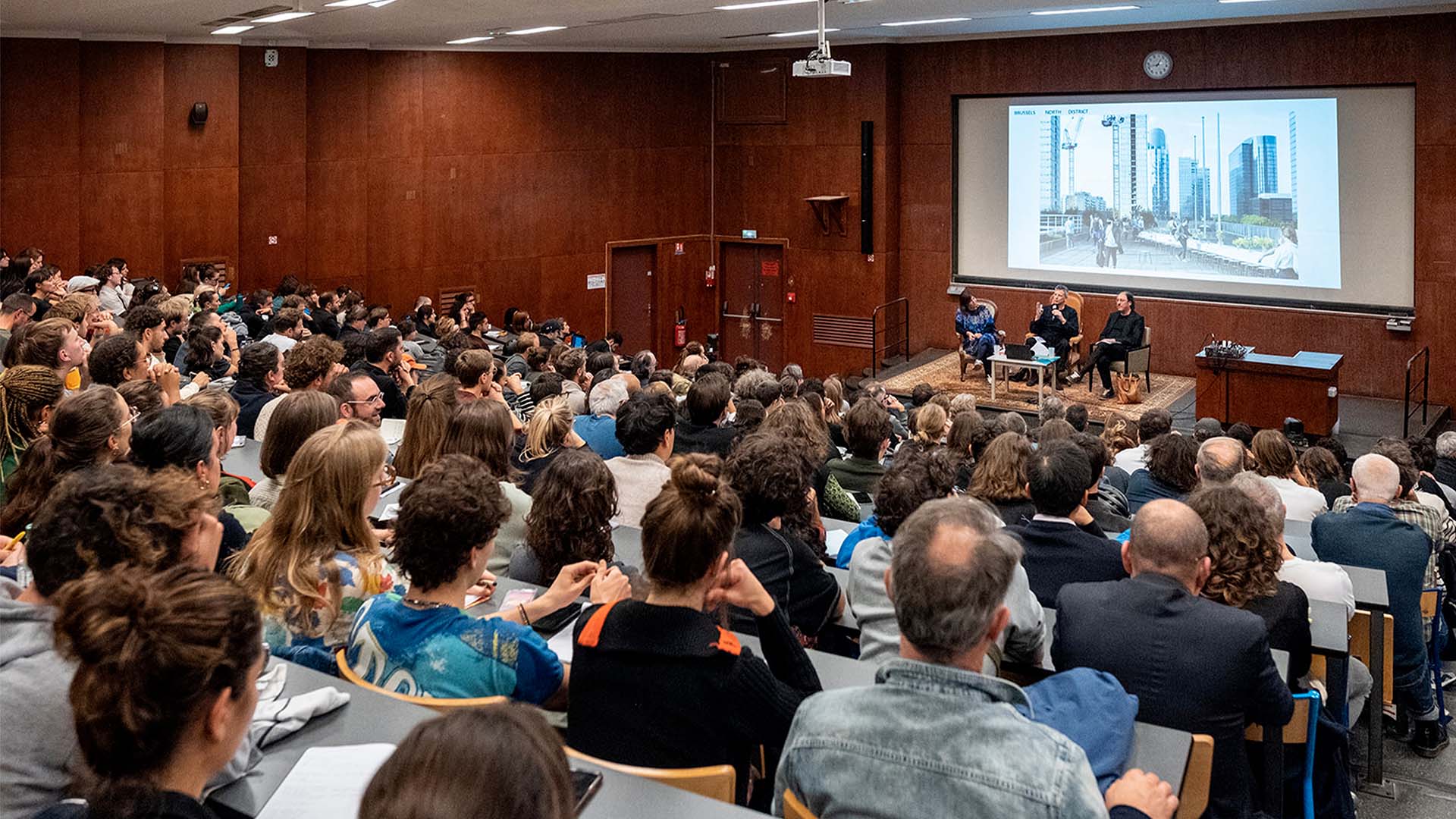 Publique écoutant trois architectes parler de leurs projets lors d'une conférence